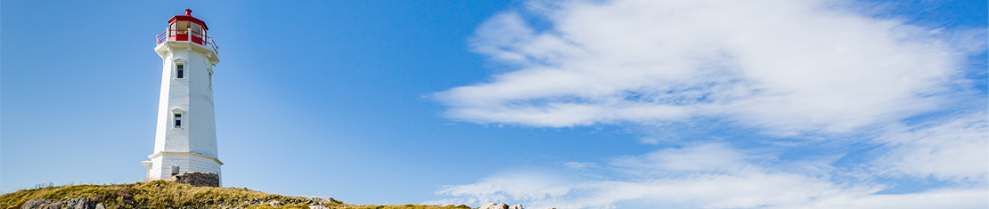 White and red lighthouse in front of a big blue sky
