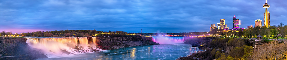Niagara falls at dusk, lit up by street lights 