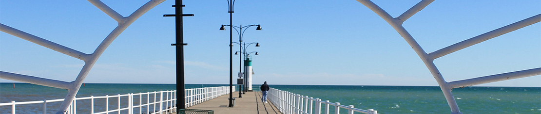Pier over a large body of water with white railings.
