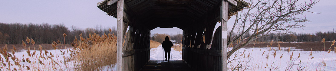 Person standing in an old covered bridge during winter